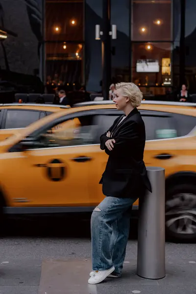 Parlak sarı bir taksi geçerken, hareketli ve canlı bir şehirde büyük bir güvenle poz veren şık bir şahıs. New York 'lu Kadın.