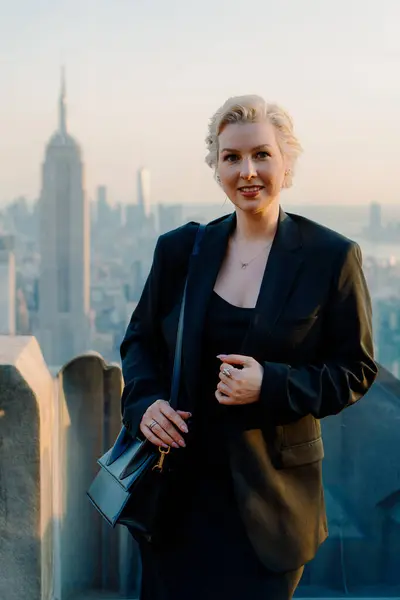 Şık ve şık bir kadın, New York 'un nefes kesen görkemli siluetine hayran kalarak çatıda duruyor.