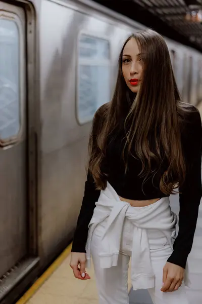 Şık ve şık bir kadın, şehir metro ortamında kendine güvenerek poz veriyor, çağdaş moda eğilimlerini sergiliyor.