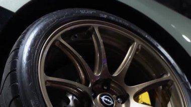 NEW YORK, ABD - 30 Mart 2024: Yüksek performanslı bir lastiğin çarpıcı bronz alaşımlı tekerleğinin yakın çekimi, zarif tasarımını güzel bir şekilde gösteriyor. Nissan GTR
