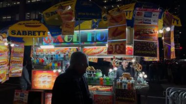 NEW YORK, ABD - 29 Kasım 2024 Canlı, hareketli bir gece sahnesi, ışıl ışıl parlayan levhalarla birlikte canlı bir sokak yemeği satıcısı sergiliyor