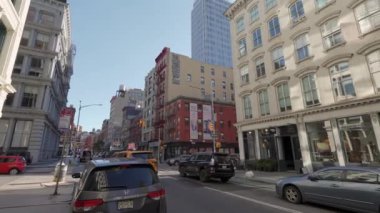 NEW YORK, ABD - 8 Aralık 2024: Canlı bir şehir sokak sahnesinde açık mavi gökyüzü altında tarihi ve modern binaların bir karışımı yer alıyor