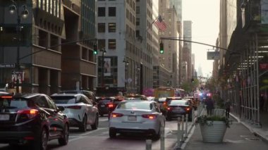 NEW YORK, ABD - 30 Kasım 2024: Yoğun trafik ve yüksek binalarla dolu hareketli bir şehir caddesi güneş batarken