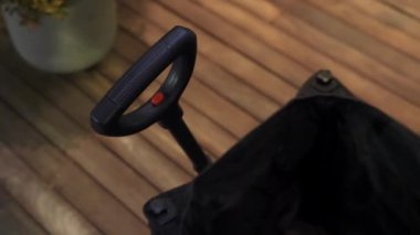 Burada modern tasarım unsurlarını sergileyen şık ve parlak siyah bir bebek arabasının yakın plan görüntüsü var.