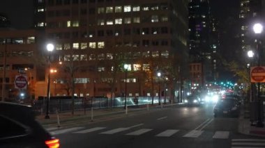 Gece boyunca hareketli ve hareketli bir şehir caddesi. Parlayan binalar ve parlak sokak lambalarıyla aydınlanıyor.