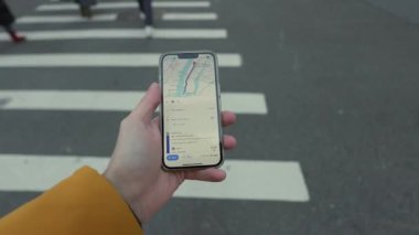 NEW YORK, ABD - 8 ARALIK 2024: Meşgul bir kentsel yaya geçidinde yol alırken haritayı gösteren bir akıllı telefonu bir kişi kavrıyor