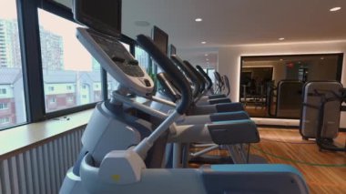Modern, parlak koşu bantları çağdaş bir spor salonunda sergileniyor. Bu spor salonunda bol miktarda doğal ışık var.