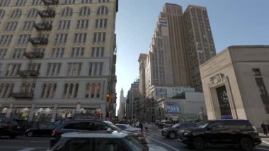 NEW YORK, ABD - 8 Aralık 2024: Canlı bir şehir sokak sahnesinde açık mavi gökyüzü altında tarihi ve modern binaların bir karışımı yer alıyor