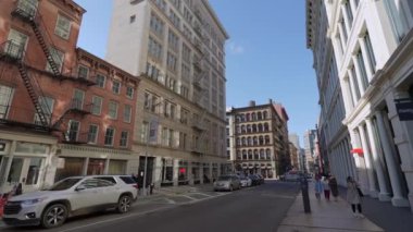 NEW YORK, ABD - 8 Aralık 2024: Canlı bir şehir sokak sahnesinde açık mavi gökyüzü altında tarihi ve modern binaların bir karışımı yer alıyor