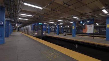 NEW YORK, ABD - 2 Aralık 2024: Şık ve modern bir metro treni yolcuların yoğun bir şehir istasyonuna gelmelerini sabırla bekliyor