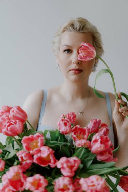 Zarif bir kadın zarif ve canlı pembe lalelerle poz verir yumuşak, rüya gibi bir arkaplana karşı. Mavi iç çamaşırlı bir kadın..