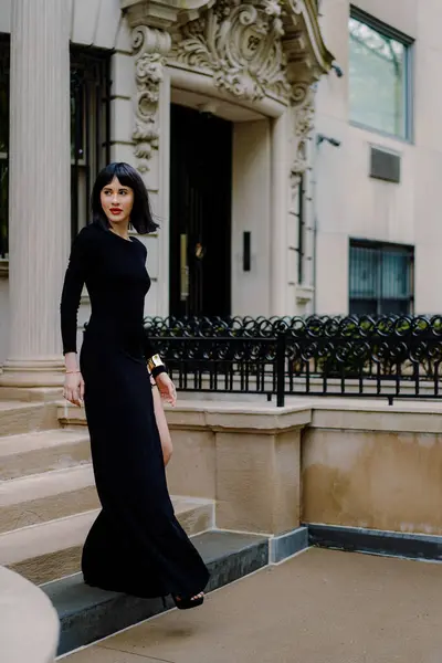 Şık ve kendine güvenen bir kadın zarif bir siyah elbiseyle zarif bir şekilde yürür.