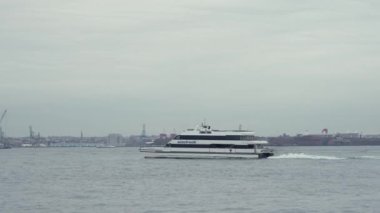 NEW YORK, ABD - 2 Aralık 2024: Zarif bir yat yumuşak, bulutlu bir gökyüzü altında sakin sularda yelken açar ve sakin bir deniz manzarası yaratır