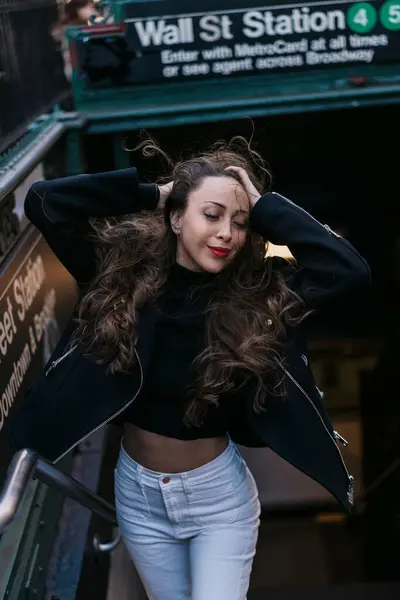 Uzun, dalgalı saçlı şık ve şık bir kadın New York 'taki kalabalık Wall Street metro girişinin önünden zarif bir şekilde geçiyor.
