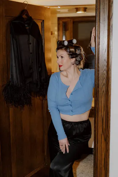 Göz kamaştırıcı ve modası geçmiş eski bir fotoğraf çekimi. Bigudileri ve şık kıyafetleri olan zarif bir modeli sergiliyor.