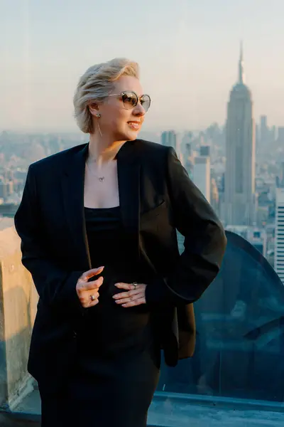 Şık ve şık bir kadın, New York 'un nefes kesen görkemli siluetine hayran kalarak çatıda duruyor.