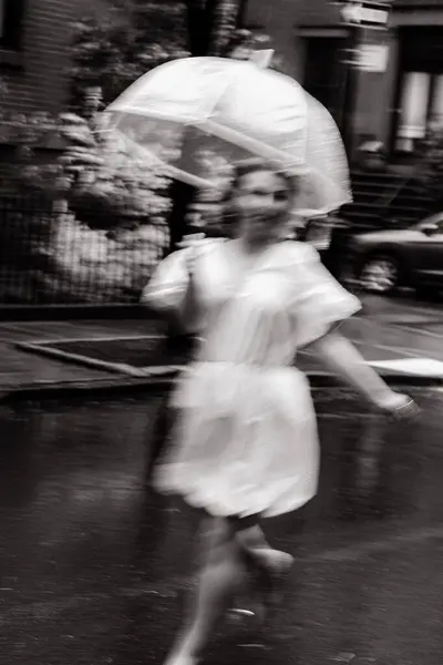 Güzel bulanık bir görüntü, elinde şemsiyeyle yağmurda yürüyen bir insanı neşeyle yakalar.