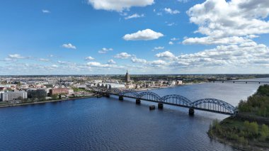 Daugava Nehri Demiryolu Köprüsü 'nden geçen elektrikli tren Riga rıhtımında rıhtım havadan görünüşü ünlü liman Rigas tarihi limanı tarihi Letonya iskelesi sevkiyatı Panoramatik bahar sezonunda