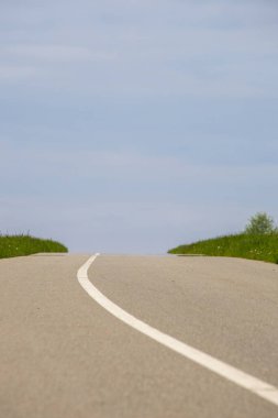 Asfalt yolu yeşil çimen ve mavi gökyüzü arka planda.