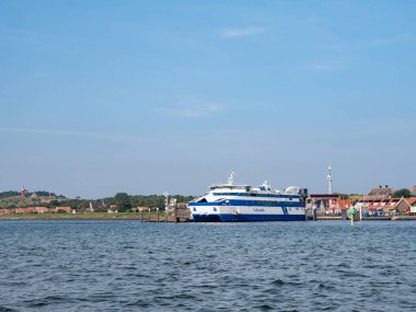 VLIELAND, NETHERLANDS - 7 SEP 2021: Vaddensea, Batı Frizya adası Vlieland 'den feribot ve deniz feneri ile Doğu-Vlieland köyü