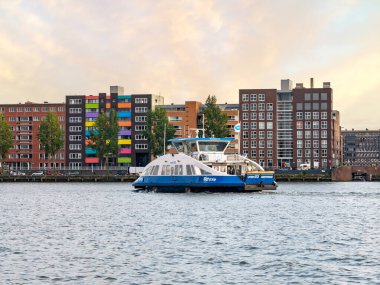 AMSTERDAM, NETHERLANDS - 20 AUG 2021: Doğu Rıhtımındaki Java Adası 'ndaki feribot ve apartmanlar