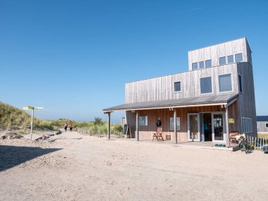 MARKER WADDEN, NETHERLANDS - OCT 8, 2021: People walking on footpath and sustainable wooden visitor centre on Marker Wadden island clipart