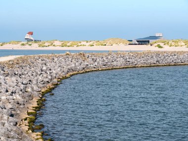 Breakwater, beach, restaurant and watch tower on coast of Marker Wadden island in Markermeer lake, Netherlands clipart