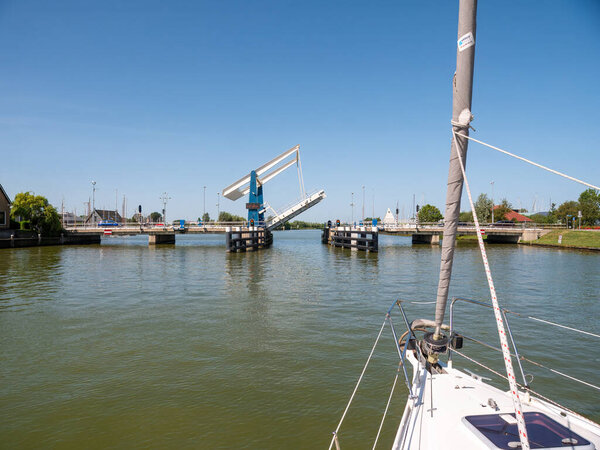 WARNS, NETHERLANDS - JUL 7, 2023: Sailboat approaching bridge waiting for opening - 2/4, Warnsebrug bridge over Johan Frisokanaal channel in Friesland, Netherlands