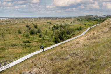 Amrum, Almanya - 27 Ağustos 2023: Amrum Adası, Kuzey Frizya, Schleswig-Holstein eyâletinde Wittdun kumullarında yürüyen insanlar