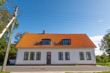 Livo, Danimarka - 13 Şubat 2023: Livo Adası, Limfjord, Nordjylland 'daki cadde boyunca kırmızı çatı kiremitleri ve elektrik kabloları bulunan beyaz ev