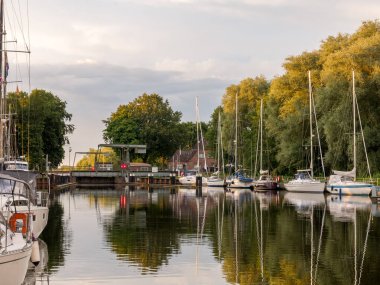 Gieselau, Almanya - 16 Temmuz 2024: Yelkenli Gieselau Kanalı ve gün batımında köprü çizmek, Holstein-Holstein