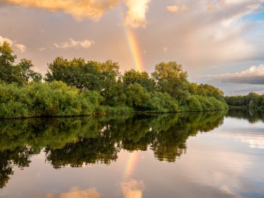 Gün batımında Gieselau Kanalı üzerinde gökkuşağı ve kara bulutlar, Almanya 'nın kuzeyinde Schleswig-Holstein