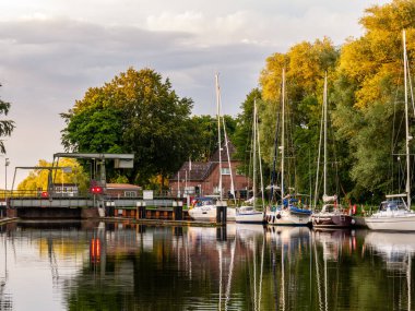 Gieselau, Germany - Jul 16, 2024: Gieselau Canal with sailboats and draw bridge at sunset, Schleswig-Holstein clipart