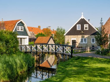 Hindeloopen, Netherlands - May 14, 2024: Scene in old town of Hindeloopen with houses and bridge over canal, Friesland clipart