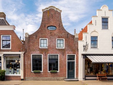 Makkum, Hollanda - 16 Mayıs 2024: Eski Makkum, Friesland 'daki Kerkstraat' ta saatli tarihi tuğla konak manzarası