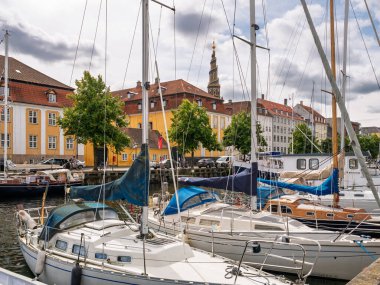 Kopenhag, Danimarka - 8 Ağustos 2024: Kurtarıcımız Vor Frelsers Kirke 'ün spiral kulesi ile Christianshavn Kanalı' na demirlemiş yelkenliler