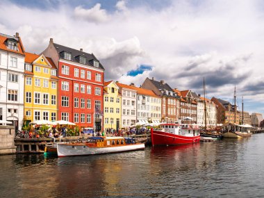 Kopenhag, Danimarka - 8 Ağustos 2024: Renkli tarihi konak evleri, demirlemiş tekneleri ve rıhtımda gezinen turistli canlı Nyhavn kanalı