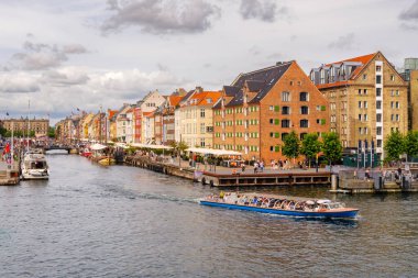 Kopenhag, Danimarka - 8 Ağustos 2024: Nyhavn Kanalı 'ndan, tarihi depolardan ve arka plandaki kanal evlerinden ayrılan turistlerle gezi teknesi