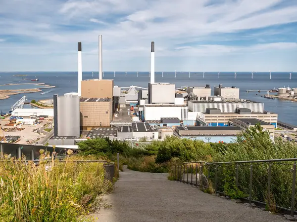 Kopenhag, Danimarka - 13 Ağustos 2024: Amagervaerket ısı ve elektrik santrali ve Kopenhag Tepesi kayak yamacından Oeresund rüzgar türbinleri