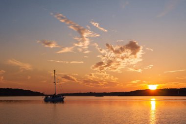 Batı Pomerania Lagoon Bölgesi Ulusal Parkı, Vorpommern-Ruegen, Almanya 'da gün batımında Barhoeft Limanı ile Bock Adası arasında, Bock Limanı' nda demirli bir tekne.