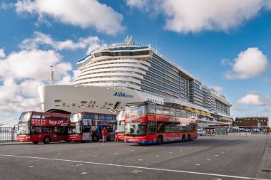 Kopenhag, Danimarka - 12 Ağustos 2024: Oceankaj Cruise Pier 'deki yolcu gemisinin önüne parketmiş dört kırmızı atlama otobüsü