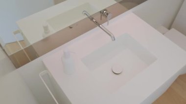 Banyoda musluğu, lavabosu ve aynası olan ahşap tezgahın üzerine kurulmuş bir tesisat. Döşeme bileşik malzemeden yapılmıştır.