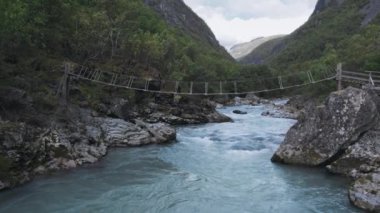 Sıcak bir günde turizm merkezinin görüntüsü, Batı Norveç 'te hafta sonu. Göz kamaştırıcı İskandinav doğası üzerine güzel bir hava aracı uçuşu, hızlı akan mavi dağ nehri, köpüklü suda kayalar.