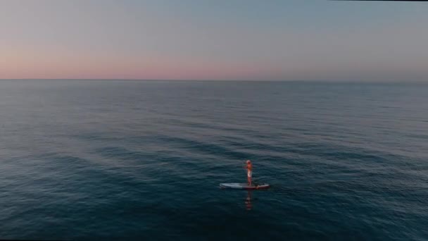 一个人在海里的船桨上航行的景象令人惊叹 日出日落时 站在Sup板上沉思而专注的活动 — 图库视频影像
