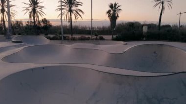 Aerial drone reveal of empty skateboard pool in sunrise or sunset in summer. Millennial modern sport activity. Cinematic California lifestyle view.