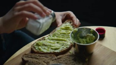 Woman in cafe has delicious breakfast, top up avocado toast on toasted rye bread with salt and pepper. Healthy and nutritious lunch or brunch in restaurant