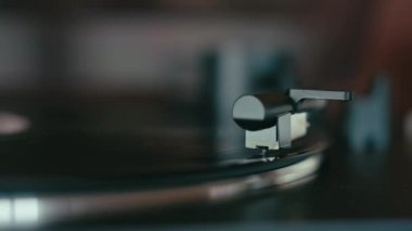Closeup on turntable stylus touching vinyl record spinning on record player. High end music equipment for analog vintage music reproduction
