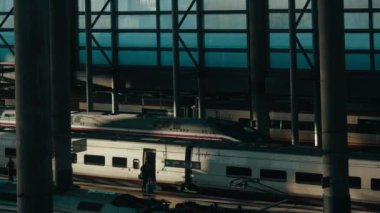 Railway high-speed train arrives at the platform. Passengers enter the wagons. Destination and transportation train hub concept. Public transport in modern life. Madrid, January 2023. 