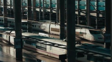 Bullet train departs from the platform of Atocha railway station in the busy hours. View of the railway track in the high-speed train hub. Tourism and transportation concept. Madrid, January 2023. 