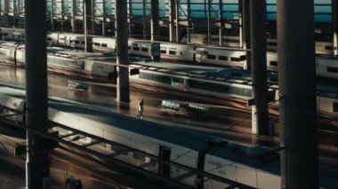 View from the top of single person with a suitcase rushing in empty platform to the high-speed train in Atocha railway station. Bullet trains waiting for depart. Madrid, January 2023. 